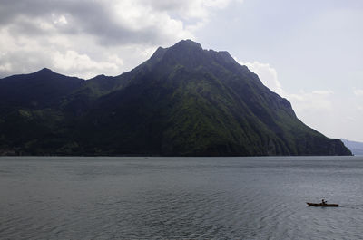 Scenic view of sea by mountains against sky