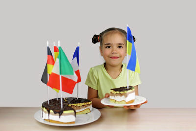 Girl holds baked cake with several european flag and ukrainian one also. europe and euro integration