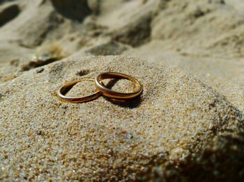 Close-up of engagement rings on sand at beach