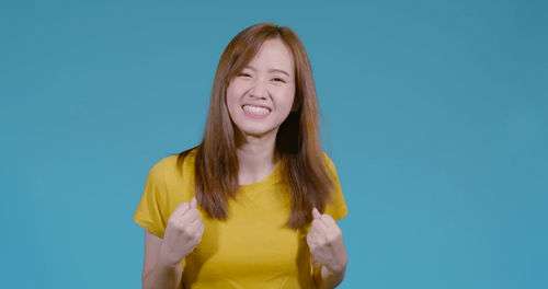 Portrait of a smiling young woman against blue background