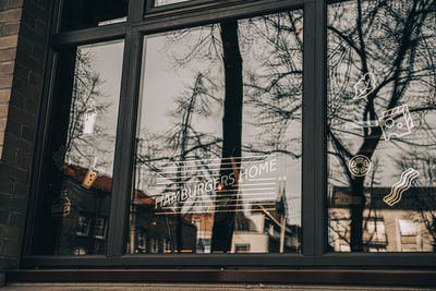 Reflection of bare trees on street seen through glass window