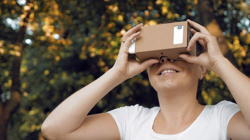 Woman using google cardboard against trees