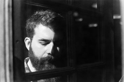Portrait of young man looking through window