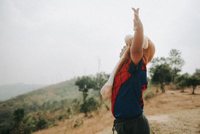 Side view of man standing on field against sky