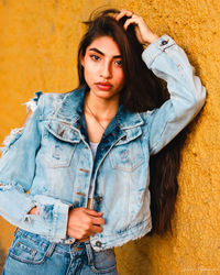 Portrait of young woman standing against wall