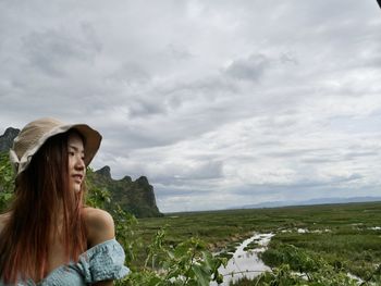 Side view of woman standing on field against sky