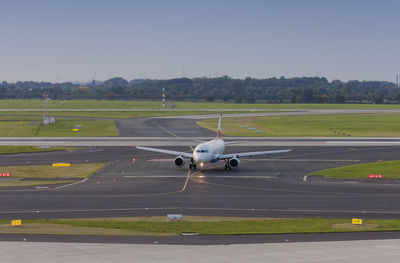 Airplane flying over runway against sky