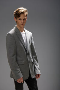 Portrait of young man standing against gray background