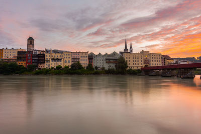 Buildings at waterfront against cloudy sky