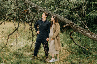 Man standing by tree trunks in forest