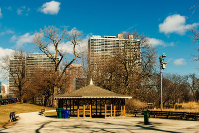 Bare trees and buildings against sky in city