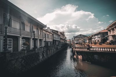 Canal amidst buildings in city against sky