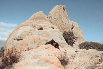 Woman lying on rock at desert during sunny day