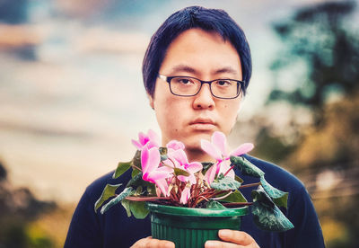 Portrait of teenage boy holding purple flowering plant