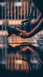 Close-up of hands photographing above reflecting pool