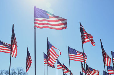 American flags blowing in the wind against blue sky