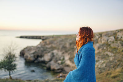 Woman standing at beach against sky