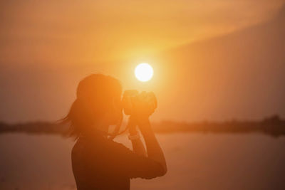 Side view of silhouette woman standing against sky during sunset