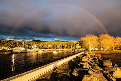 Scenic view of rainbow over river against sky