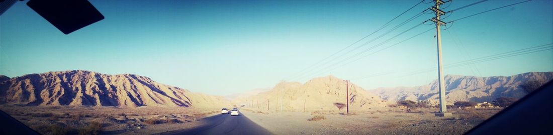 Country road leading towards mountains against blue sky