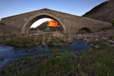 Arch bridge over river against sky