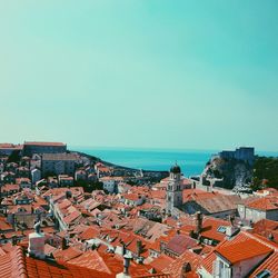 Cityscape by sea against clear blue sky