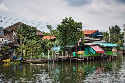 Houses by river and buildings against sky