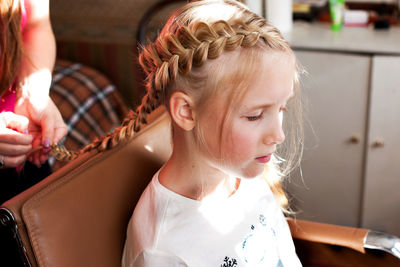 Close-up beautician braiding hair of girl 