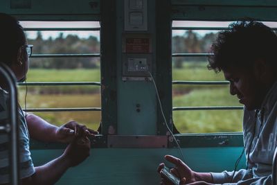 Side view of men sitting in train by windows