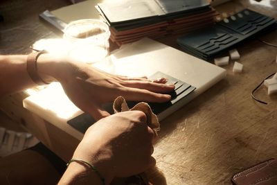 Cropped hands cleaning wallet on desk in office