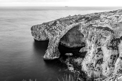 Scenic view of rock formation in sea against sky