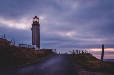Empty road with lighthouse against clouds