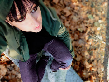 High angle view of woman looking away while sitting outdoors