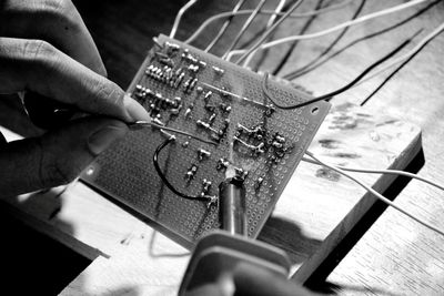 Cropped hands of man repairing circuit board at table