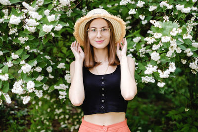 Portrait of beautiful young woman standing against plants