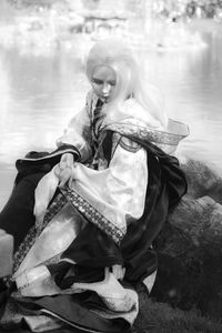 Young woman wearing costume sitting on rock