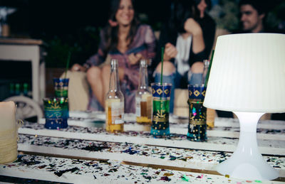 Drinks on table against friends sitting on sofa during party