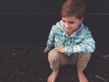 High angle view of smiling boy sitting on field