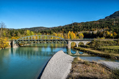 Arch bridge over river against clear blue sky