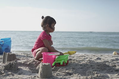 Side view of girl playing with toys at beach