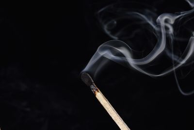 Close-up of matchstick smoke against black background