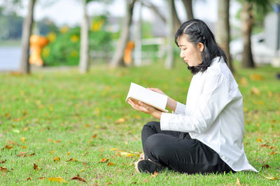 Side view of woman sitting on book