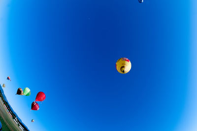 Low angle view of balloons flying against blue sky