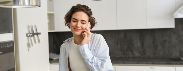 Portrait of young woman standing against wall