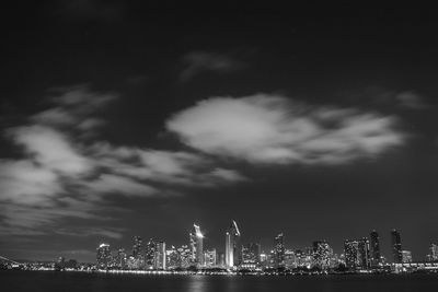Illuminated city against cloudy sky