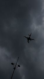 Low angle view of silhouette flying in sky