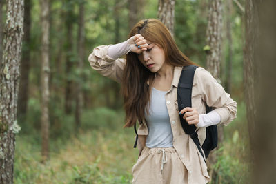 Young woman standing against trees in forest