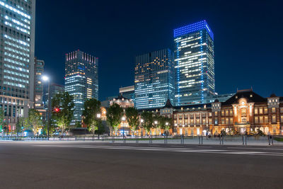 Illuminated city buildings against sky at night