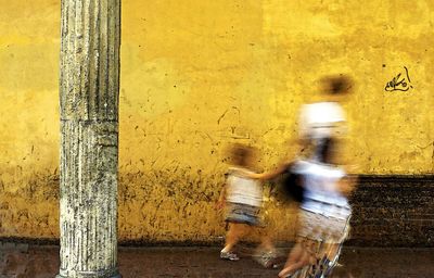 Blurred motion of family against yellow wall