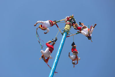 Low angle view of kites flying against clear blue sky